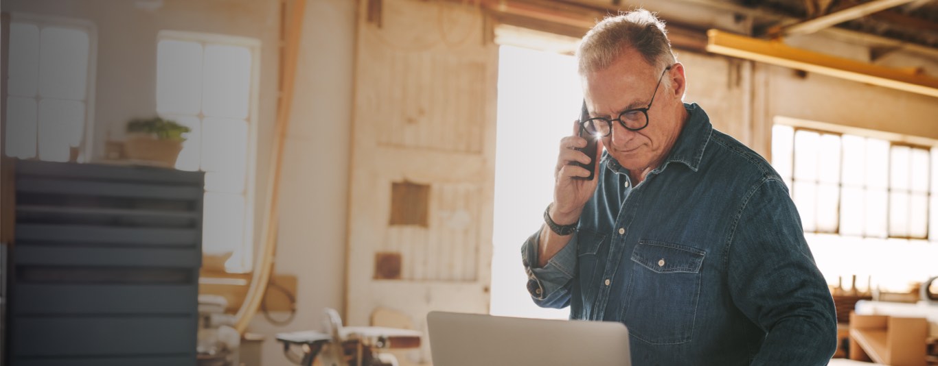 Older professional man with glasses on a phone call in a workshop
